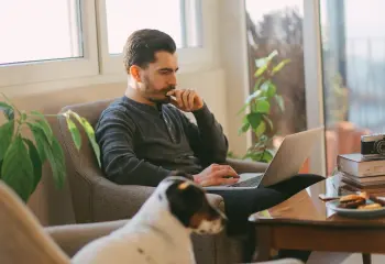 mann-sitzt-am-sofa-mit-laptop-und-hund