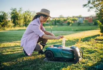 Frau schaltet Rasenroboter ein